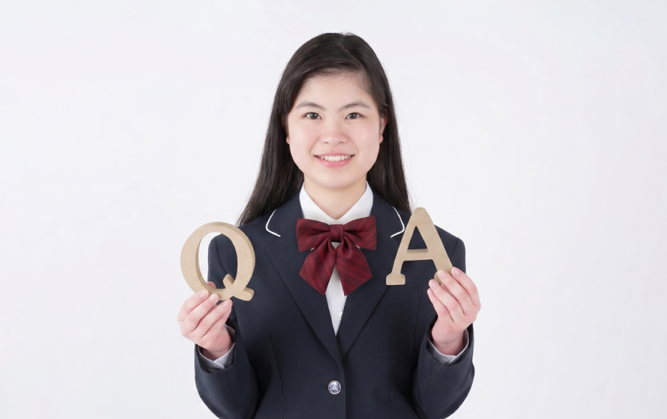 QとAの文字を持つ制服姿の女性